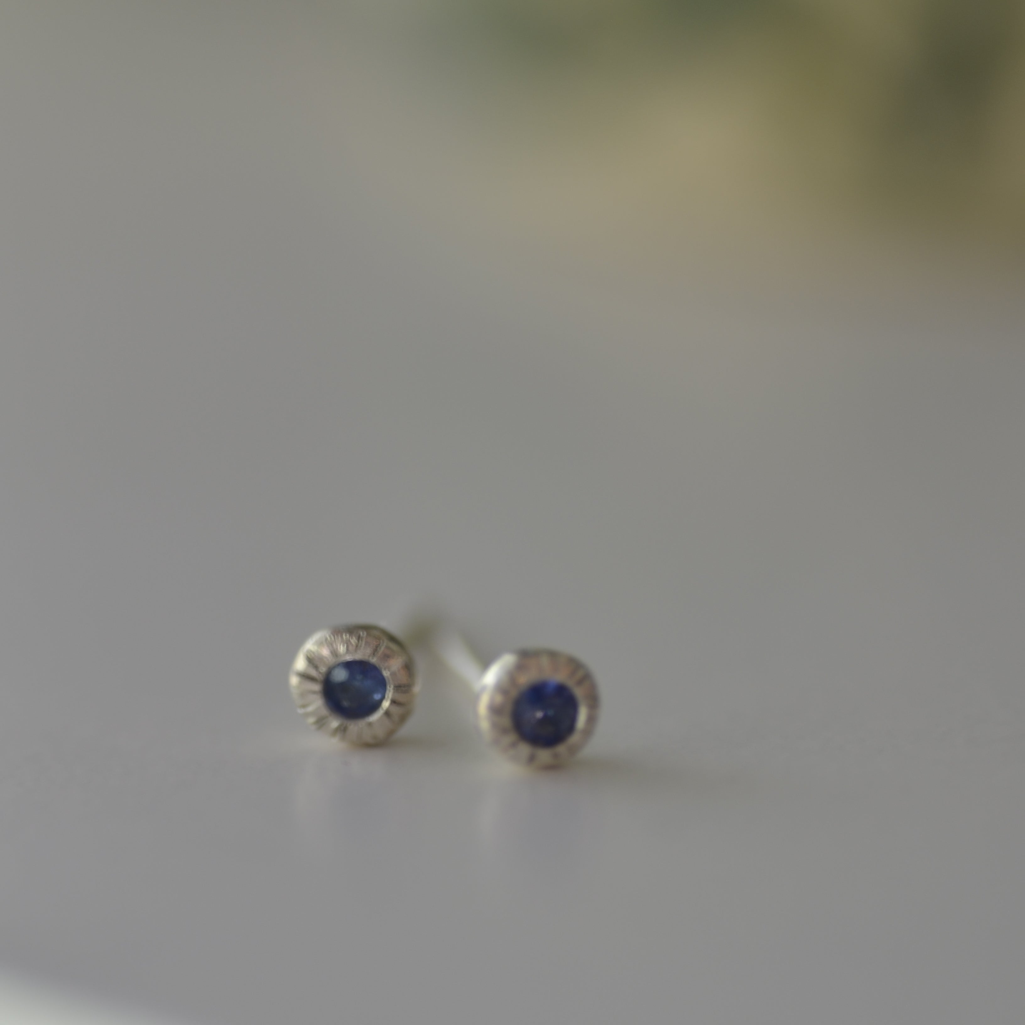 Silver earrings with blue gemstones on a light gray background