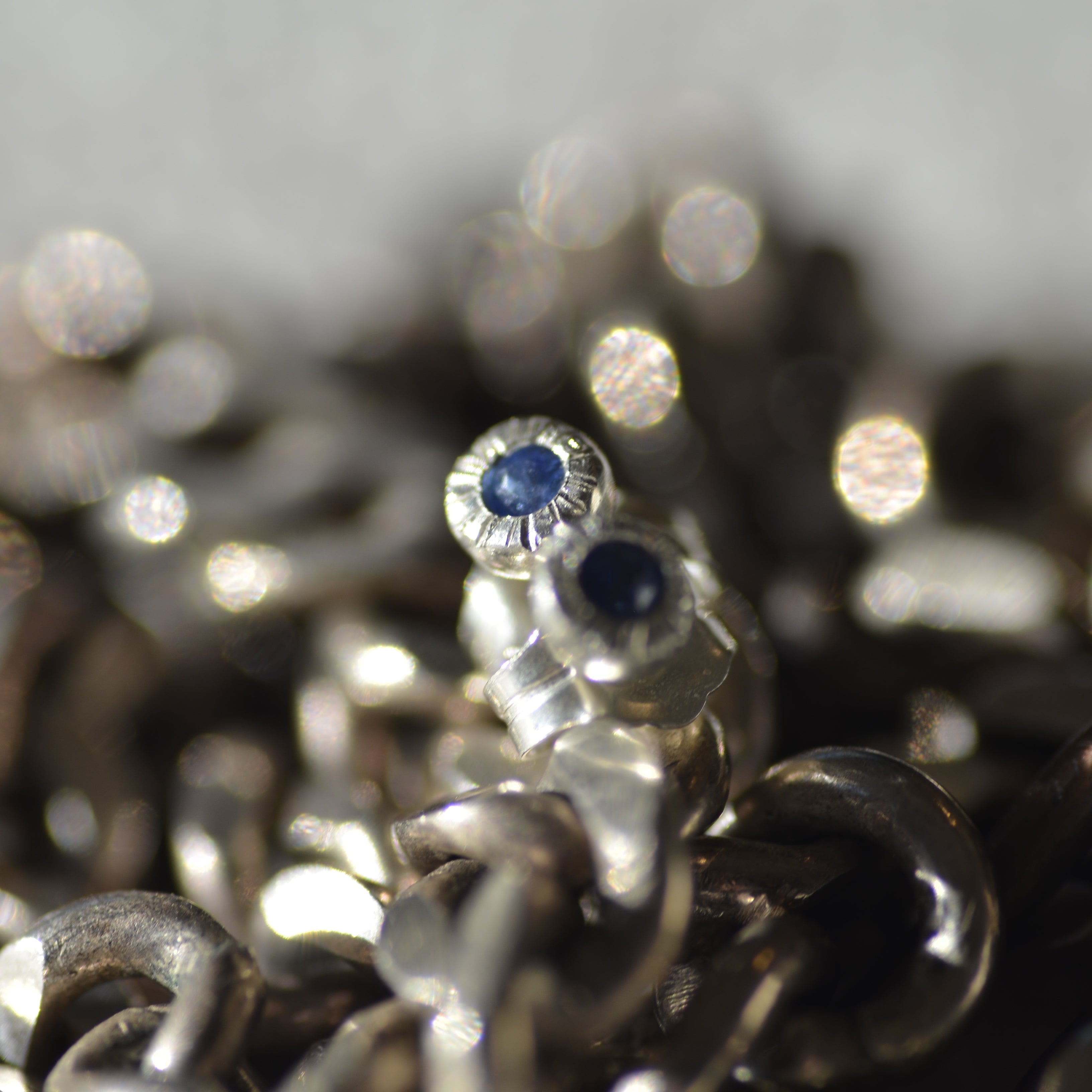 Close-up of silver jewelry with blue sapphire gemstones on a blurred background