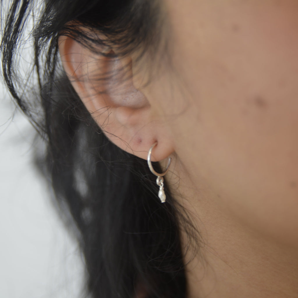 Close-up of an ear with a small earring, hair partially covering the face.