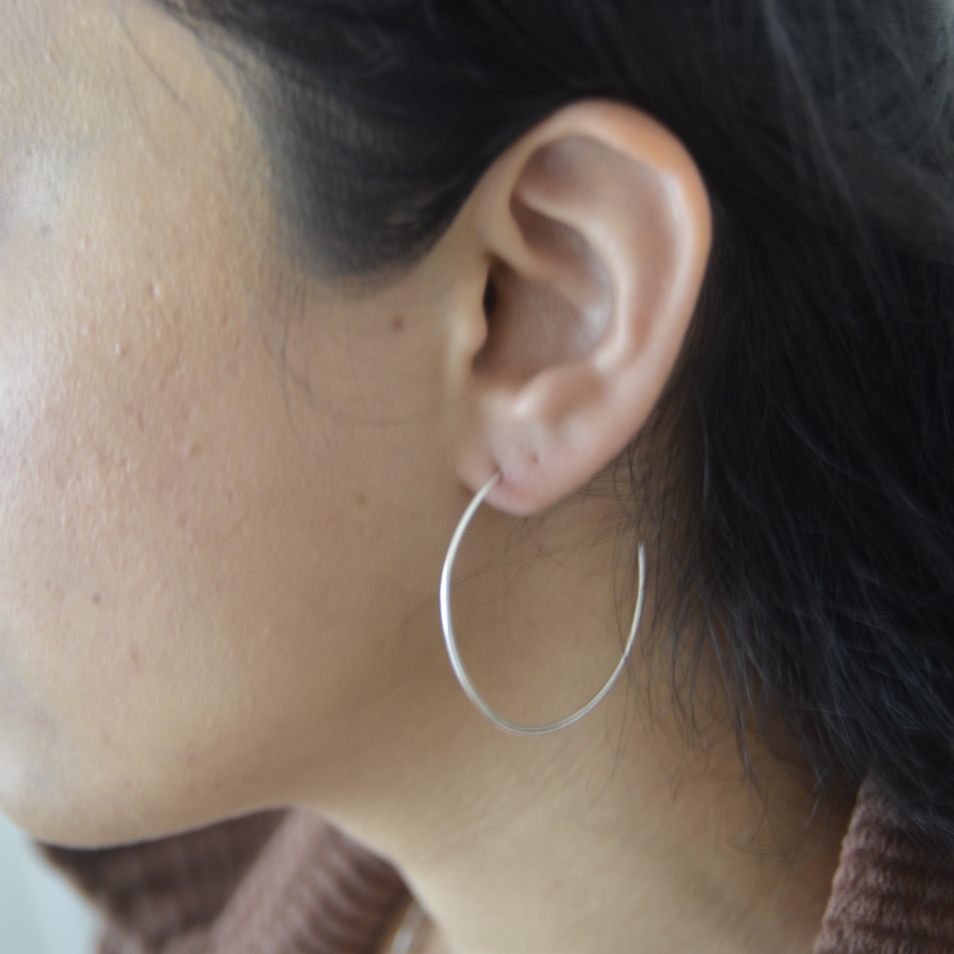 Close-up of an ear with a hoop earring, hair partially covering it.