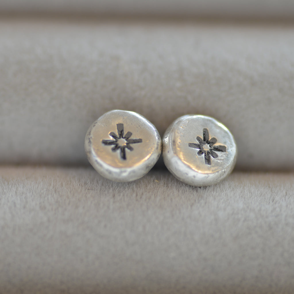 Silver earrings on a textured beige surface
