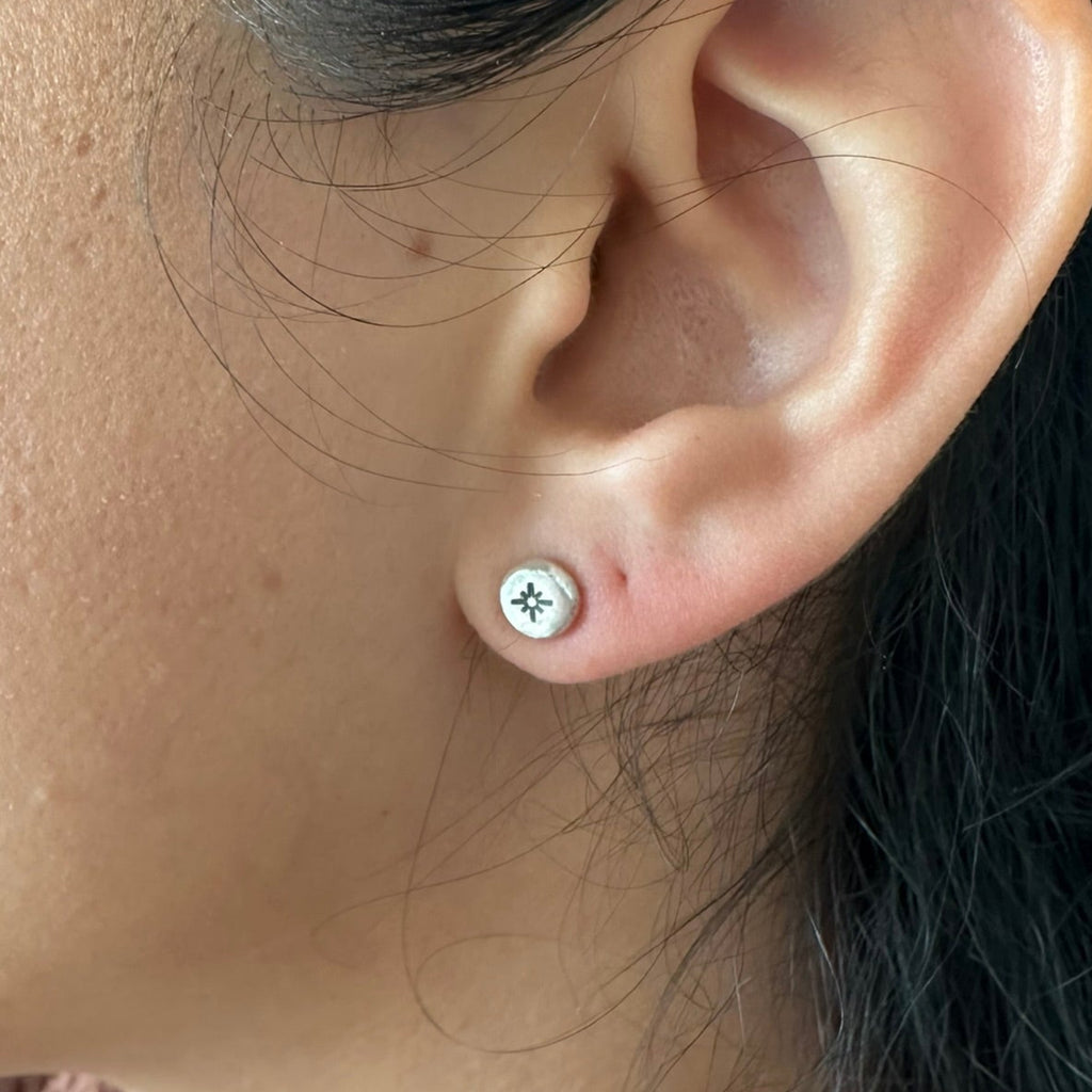 Close-up of an ear wearing a silver earring with a star design.