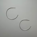 Two silver hoop earrings on a gray background