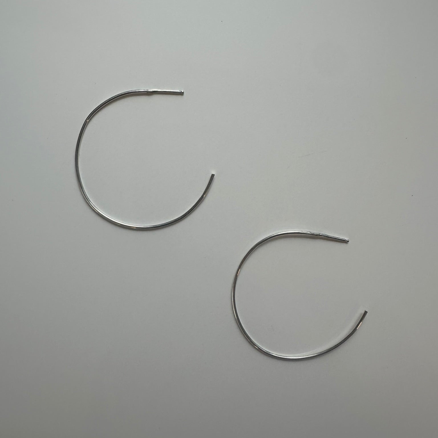 Two silver hoop earrings on a gray background