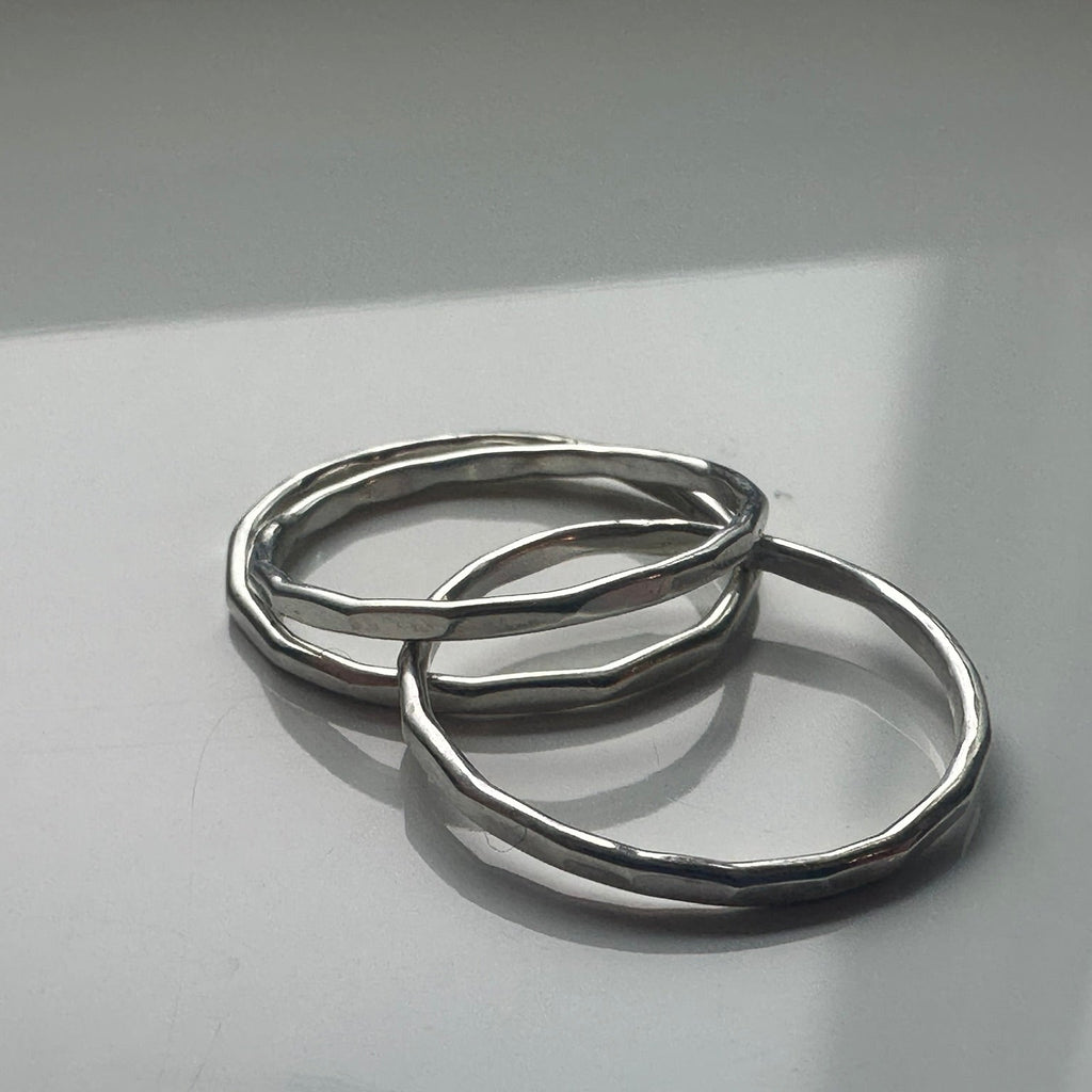 three silver rings on a reflective gray surface